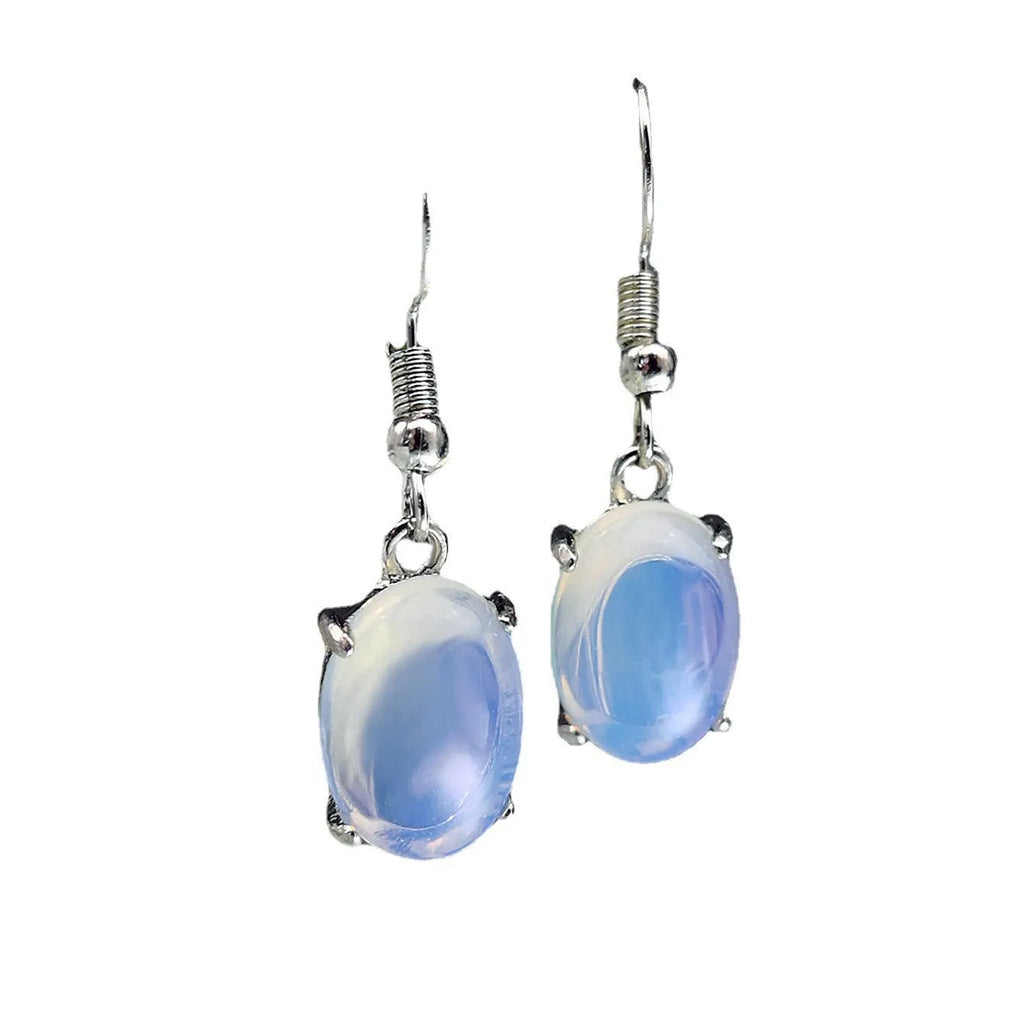 A pair of opal-coloured dangle earrings with a cross pendant, in a drop shape on a white background.