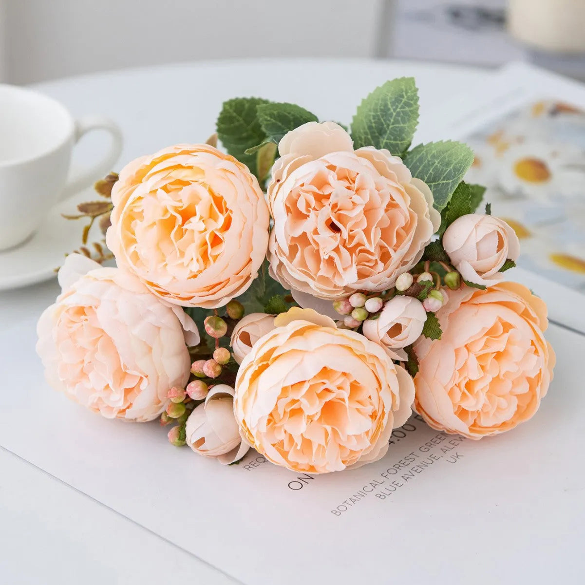 Artificial silk peony bouquet in champagne colour on a table.