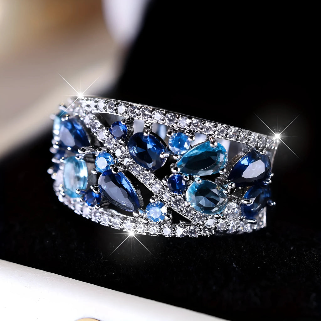 Women's round hollow ring with a gemstone, shown in gold and platinum with blue and white stone options.
