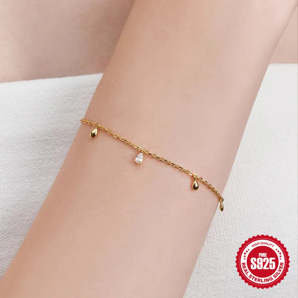 Gold plated sterling silver bracelet with a water droplet shaped diamond pendant on a woman's wrist