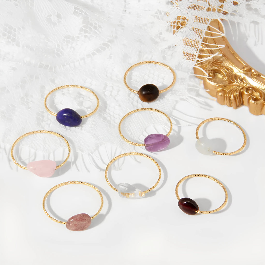 A geometric silver-toned ring setting holding a polished oval agate stone in a blue-green colour.