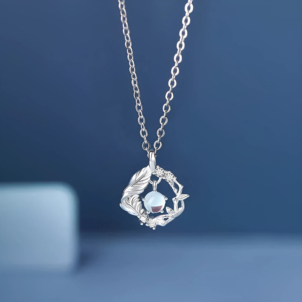 Women's geometric tree and bird pendant necklace with adjustable chain on a blue background.