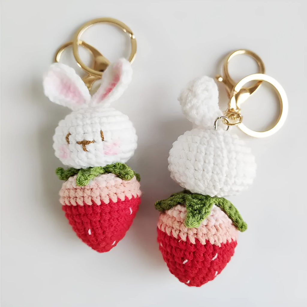 White hand-woven rabbit and strawberry wire pendant with an attached key.