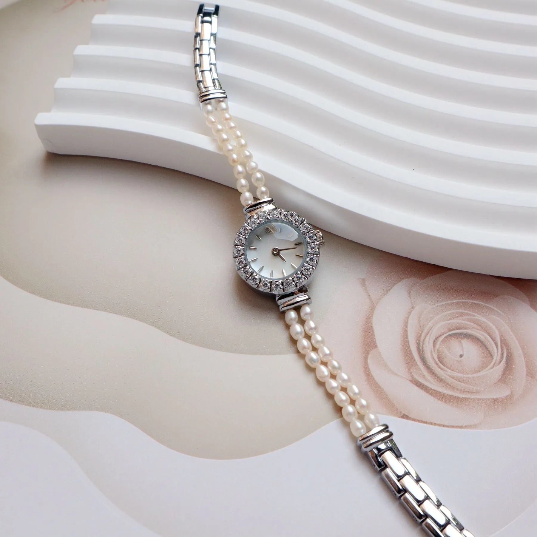 Light gold women's watch with a stainless steel strap featuring integrated freshwater pearls and a round white dial.