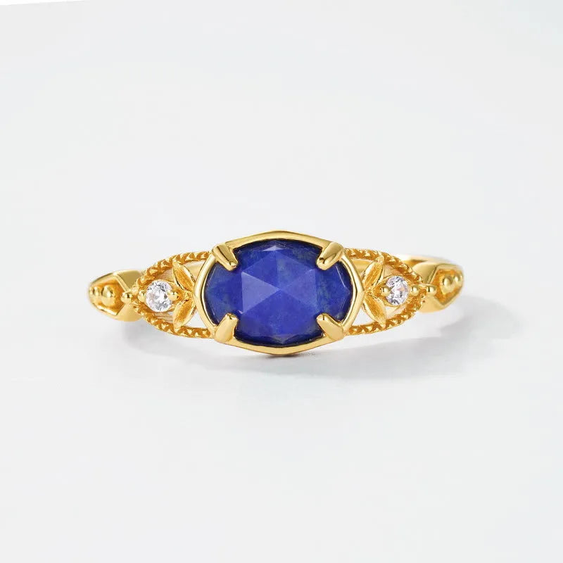 Close-up of a silver alloy ring with an elliptical geometric shape and a central natural lapis lazuli stone.