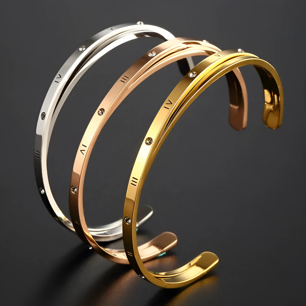 Open-ended stainless steel bracelet with a love symbol and zircon stones in gold tone.