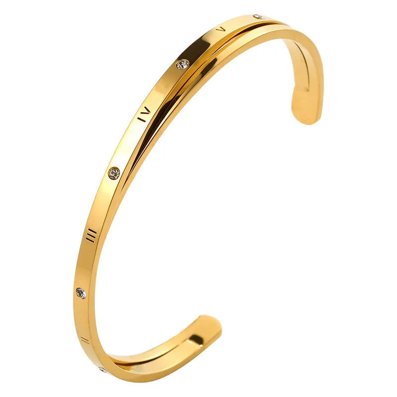 Open-ended stainless steel bracelet with a love symbol and zircon stones in gold tone.