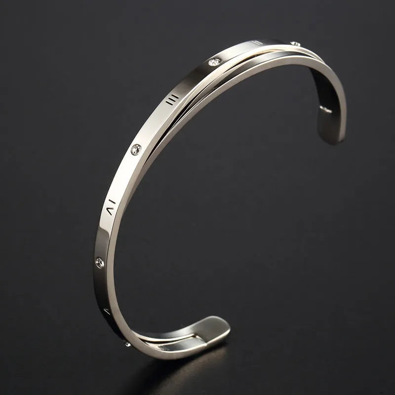 Open-ended stainless steel bracelet with a love symbol and zircon stones in gold tone.