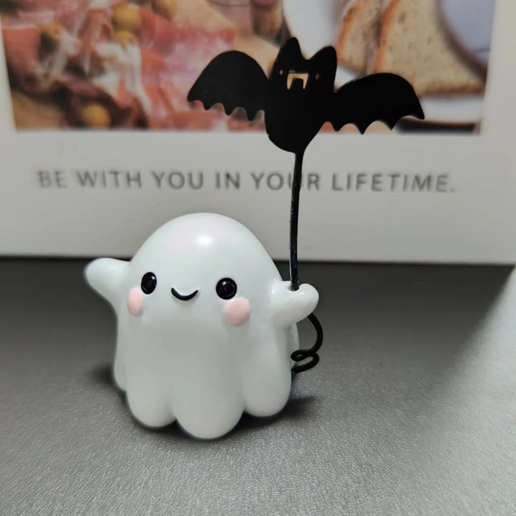 Miniature resin statue of a walking ghost dog holding a bat, a Halloween decoration.