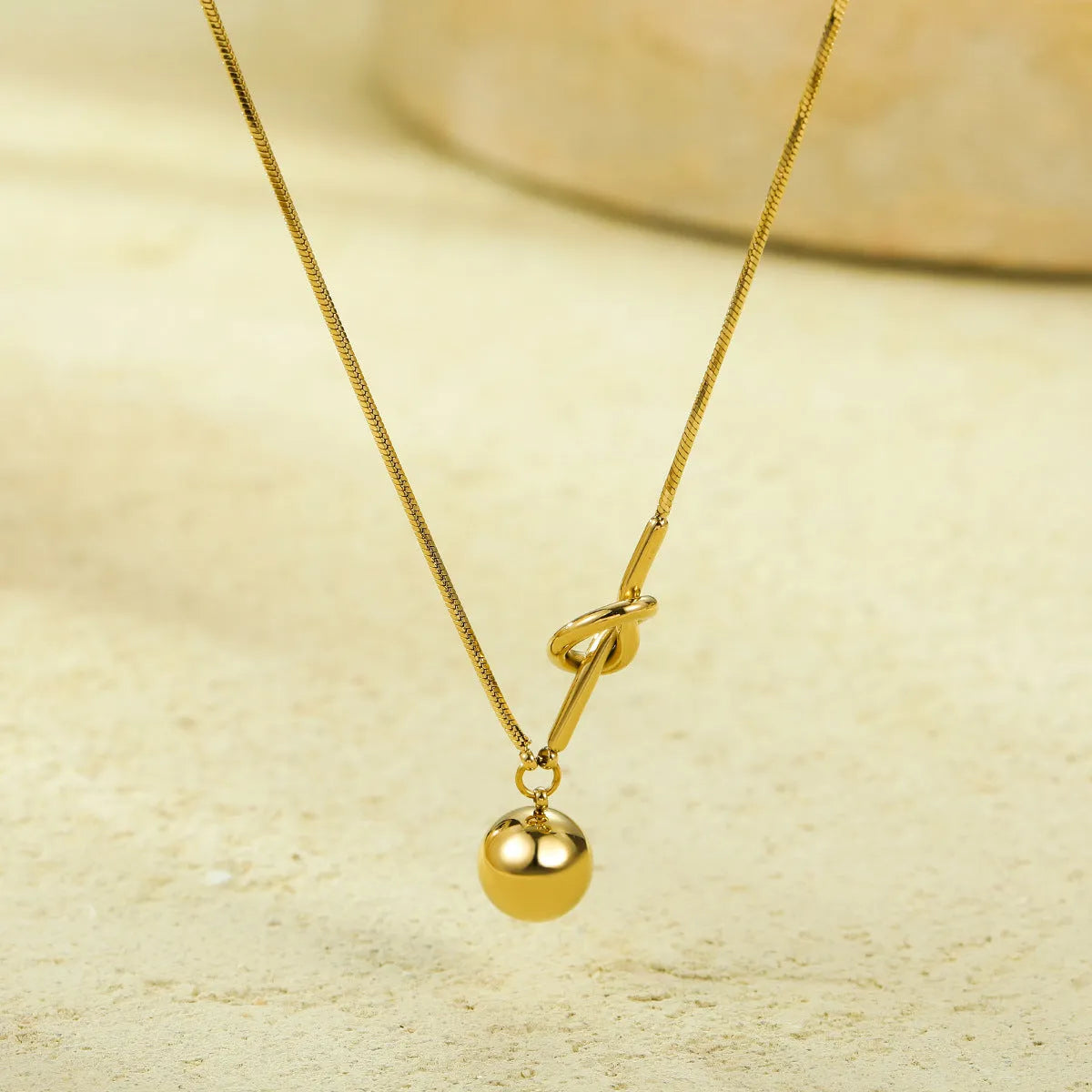 18K gold plated stainless steel winding ball pendant necklace for women on a white background