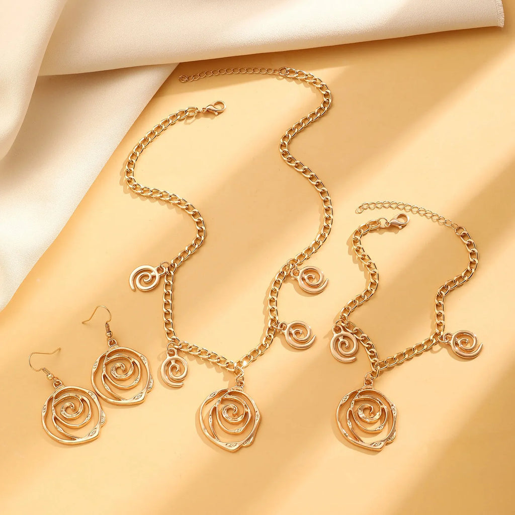 Gold spiral donut charm jewellery set showing necklace, bracelet and earrings on a white background