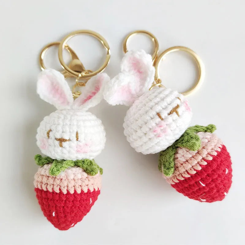 White hand-woven rabbit and strawberry wire pendant with an attached key.