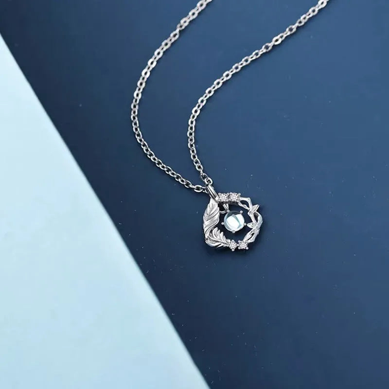 Women's geometric tree and bird pendant necklace with adjustable chain on a blue background.