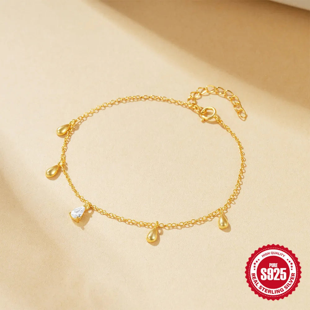 Gold plated sterling silver bracelet with a water droplet shaped diamond pendant on a woman's wrist