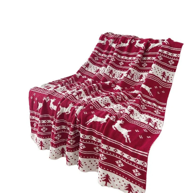 Personalised Christmas blanket with snowflake or reindeer pattern on a sofa.