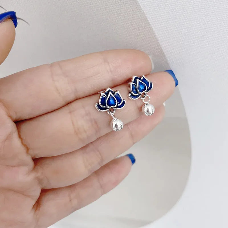 Close-up of blue lotus flower stud earrings with a silver tassel drop on an alloy ear post.