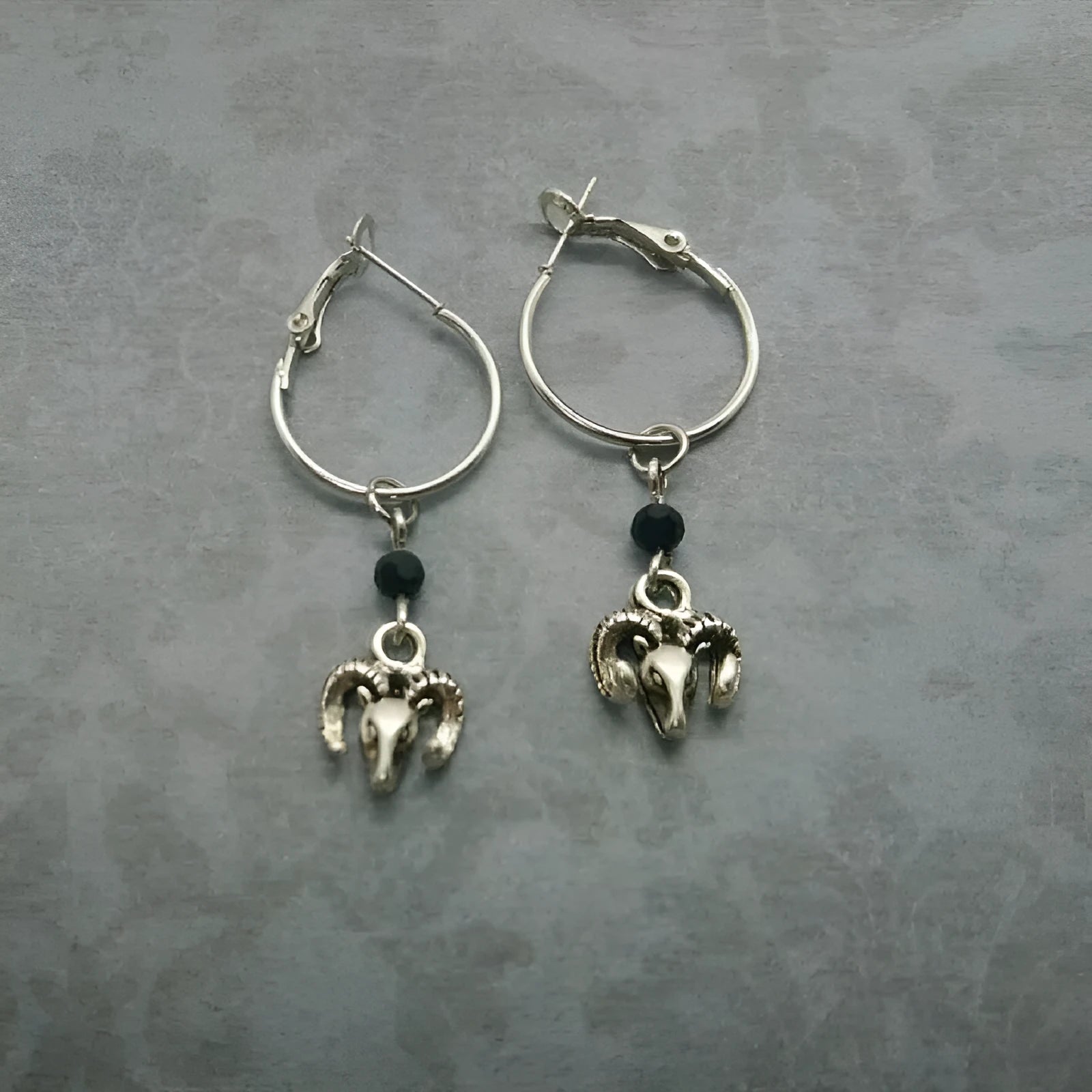 A pair of silver-coloured alloy round ring earrings for women with a Tibetan antelope design influence.