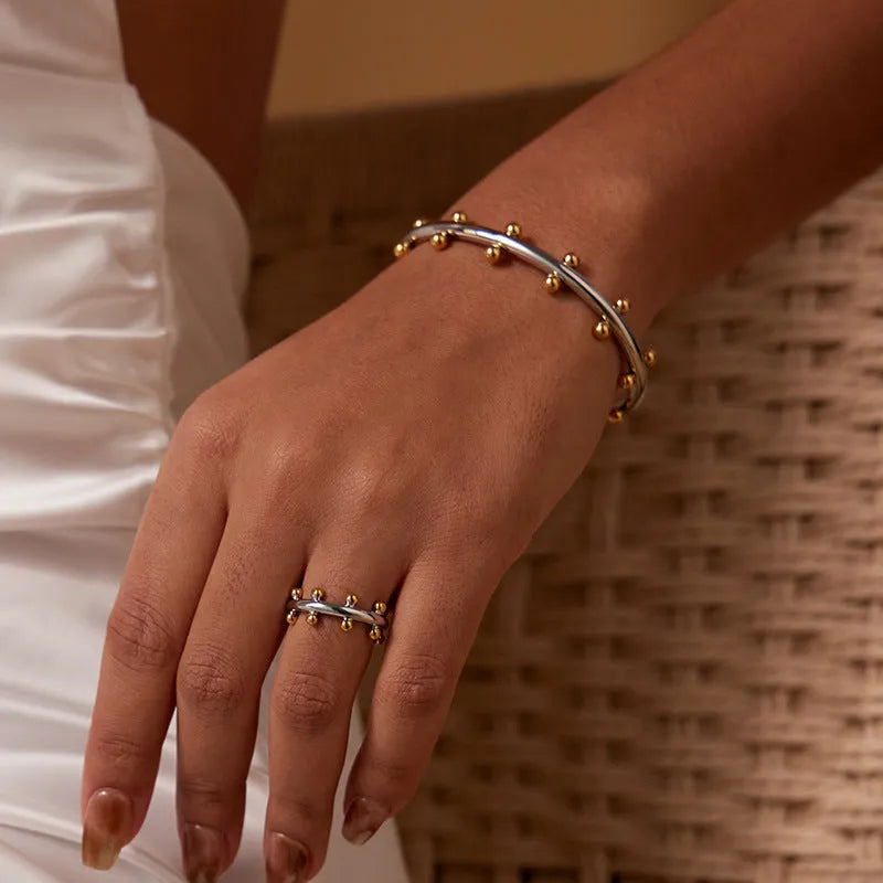 C-shaped stainless steel bracelet charm with textured surface and rivet bean beads in metallic finishes