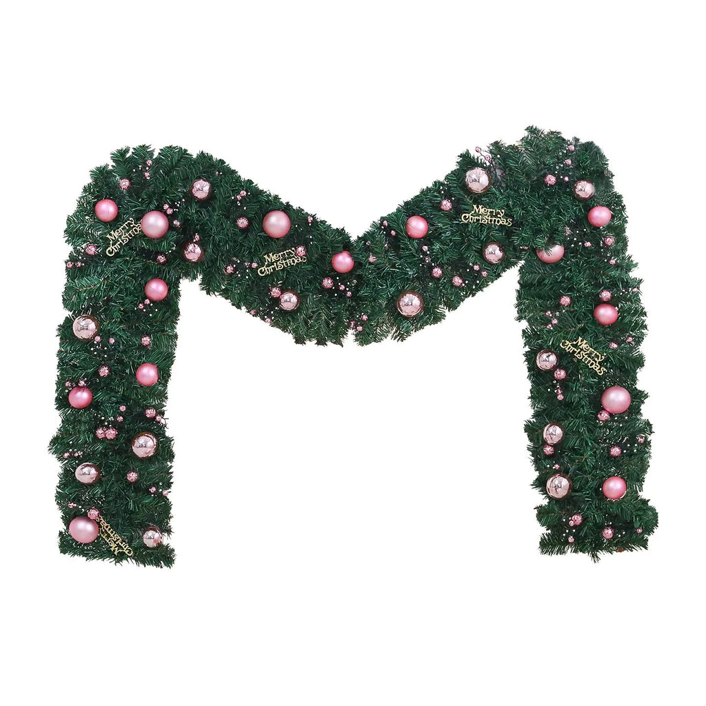 Pink artificial Christmas rattan vine decoration with small fruit clusters and warm white LED lights, coiled on a table.