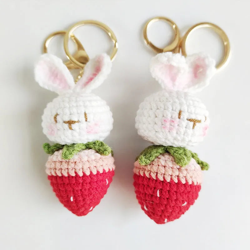 White hand-woven rabbit and strawberry wire pendant with an attached key.