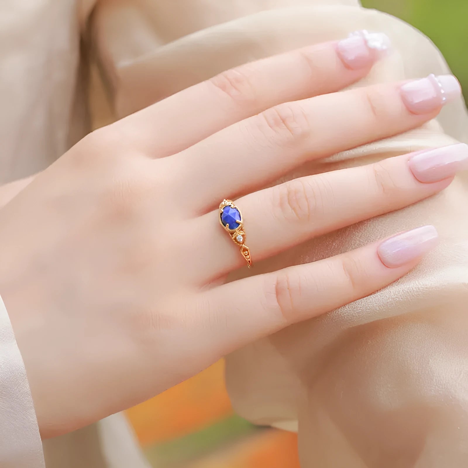 Close-up of a silver alloy ring with an elliptical geometric shape and a central natural lapis lazuli stone.