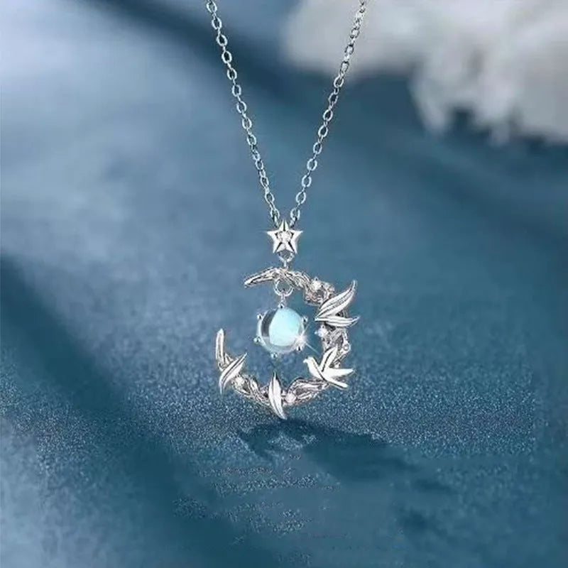 Women's geometric tree and bird pendant necklace with adjustable chain on a blue background.