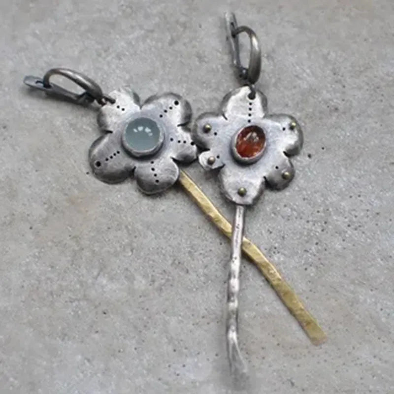 A pair of long retro-style earrings with a geometric floral shape in an asymmetric two-tone colour finish.