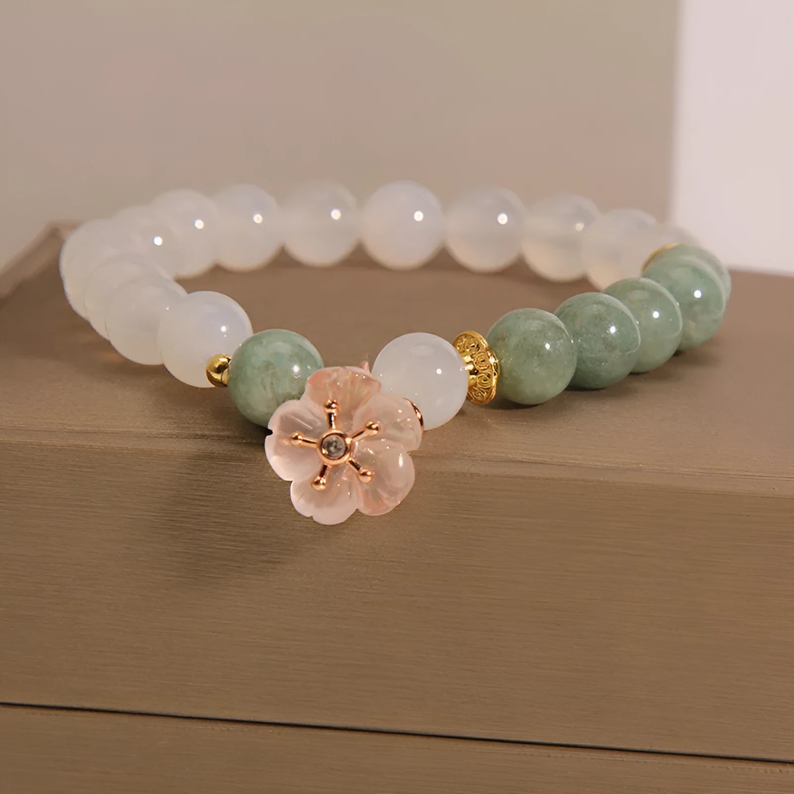 Emerald agate bracelet with white jade flower beads and pink accents on wrist