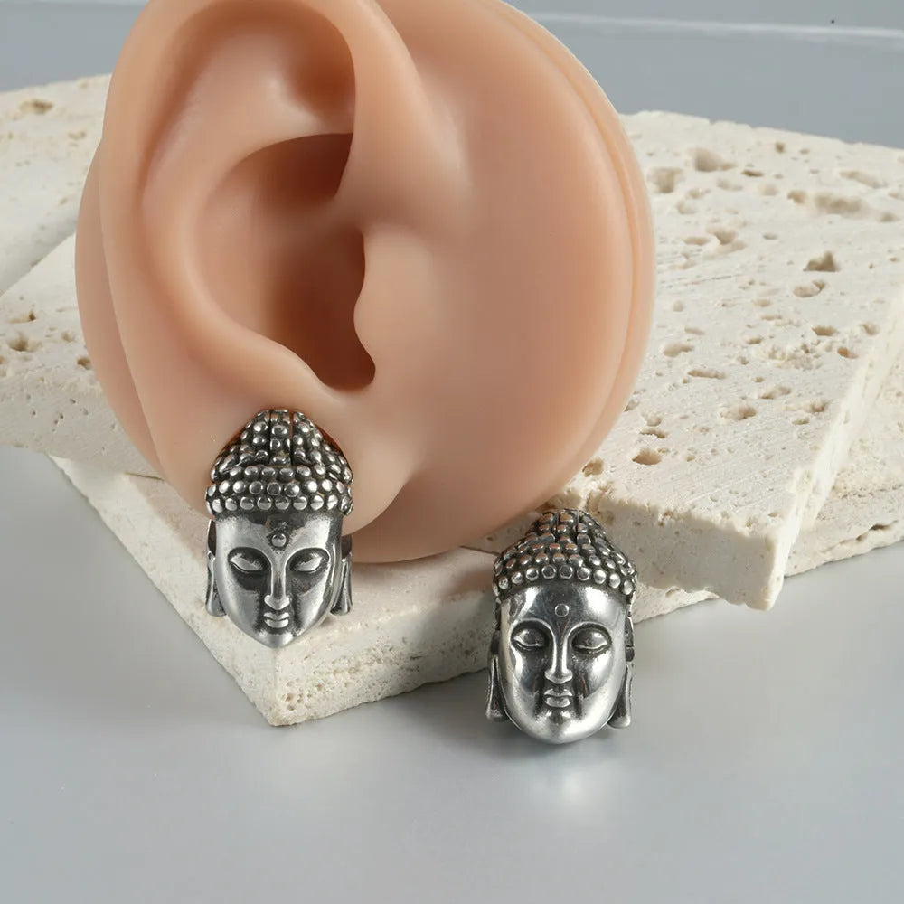 Stainless steel hollow skull and Buddha head earrings in hip hop style.