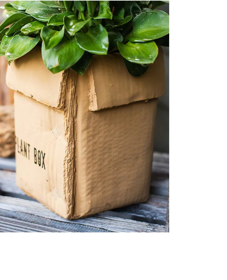 Cement flowerpot with brown paper carton design and drainage hole for indoor balcony plants.