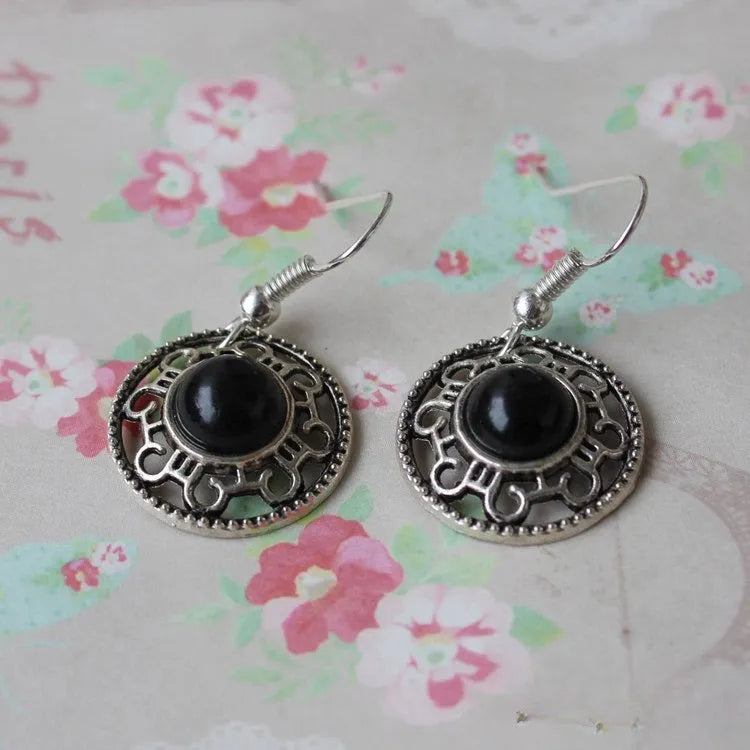 Handmade Miao silver retro earrings with turquoise flower disk and ethnic patterns in black.