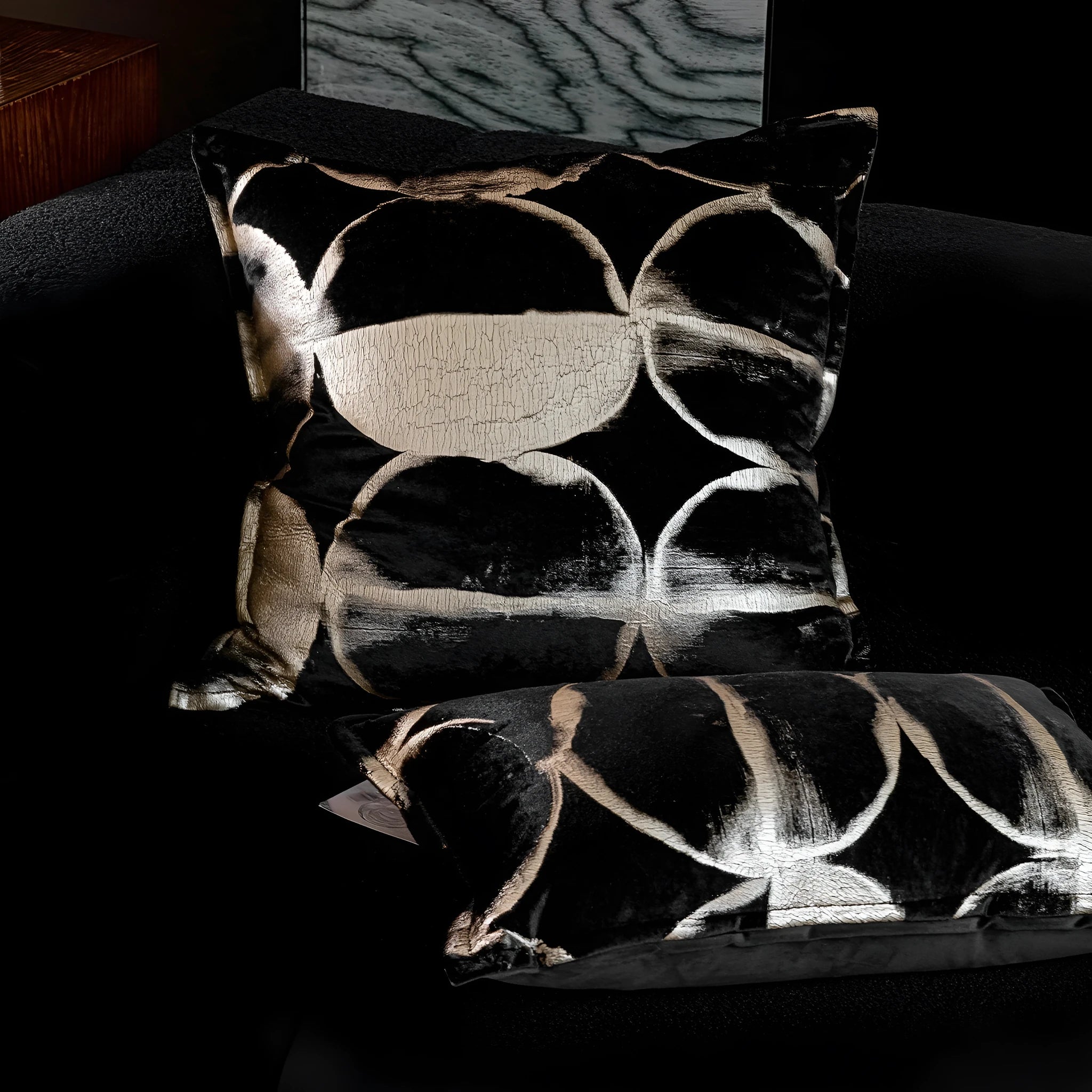 Black gold abstract pattern decorative cushion with removable cover in 45x45cm square size on a grey sofa.