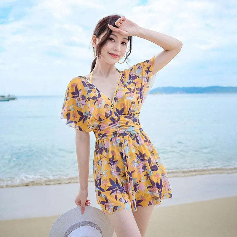 Yellow floral patterned women's one-piece swimsuit on a hanger, showing front design.
