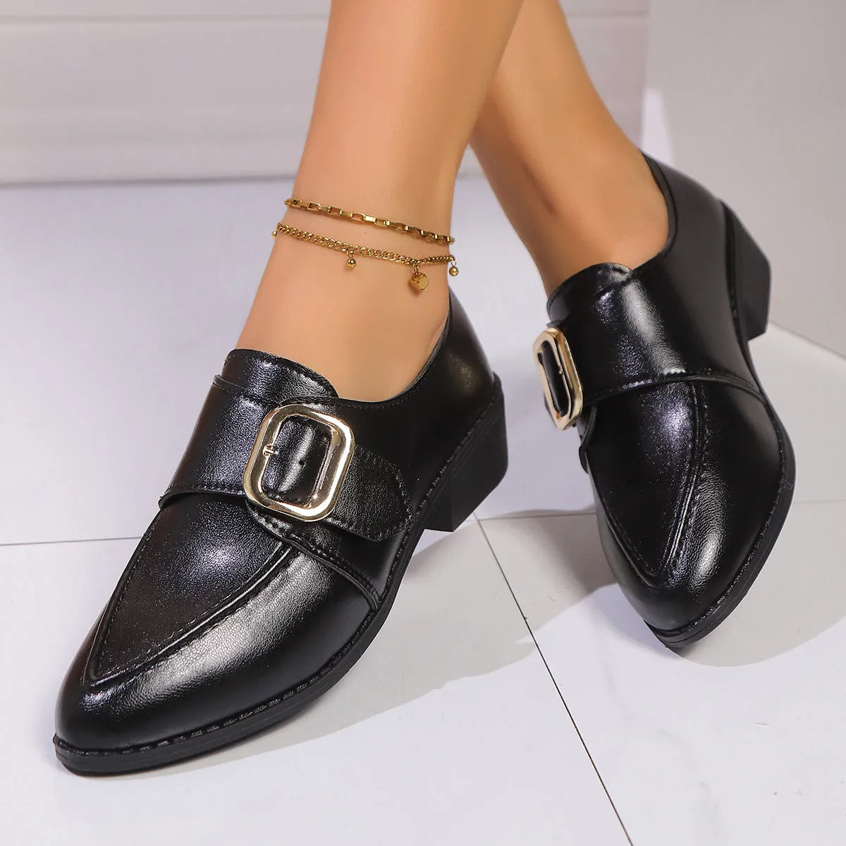 Women's black leather-look flat shoes with a decorative bow on the pointed toe.