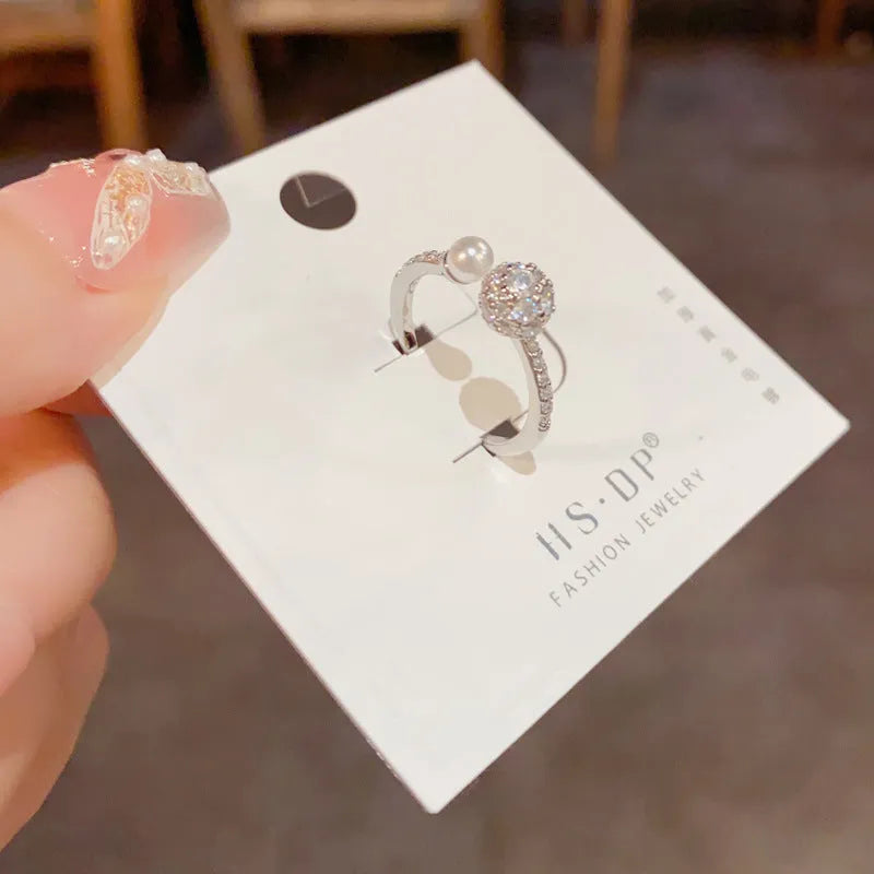 Gold or silver open-end pearl ring with round zircon detailing on a geometric band.