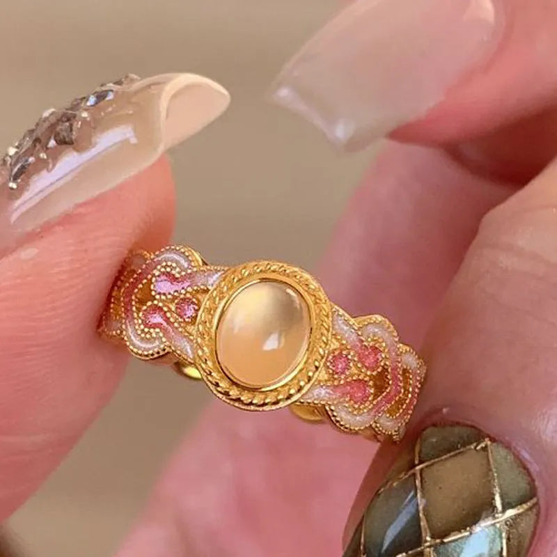 Gold geometric open ring with a pink crystal enamel stone on a model's finger.
