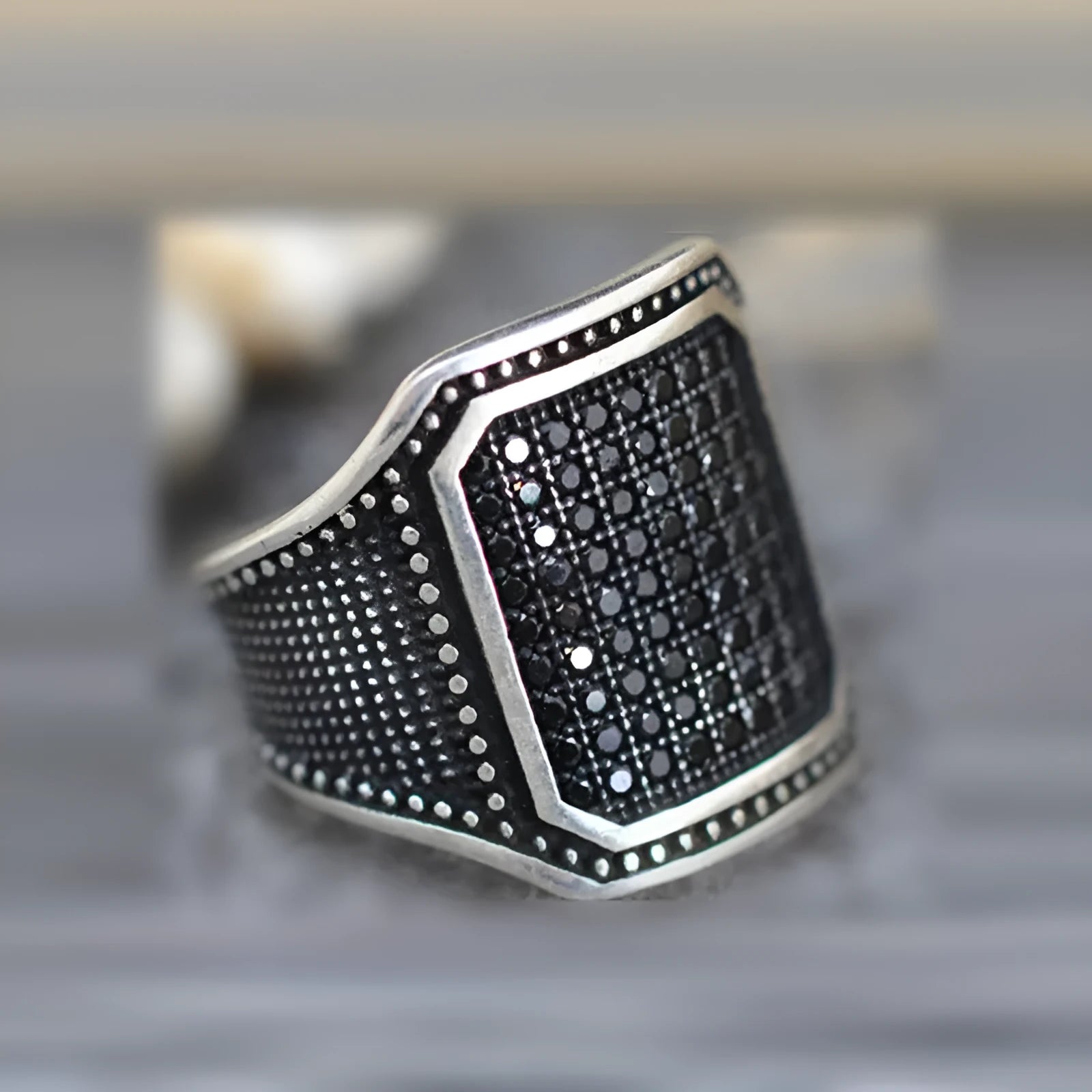 Black alloy ring with copper detailing and a zircon stone, shown in a unisex style.