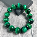 Green Tiger Eye stone beaded bracelet with polished geometric beads on a white background.