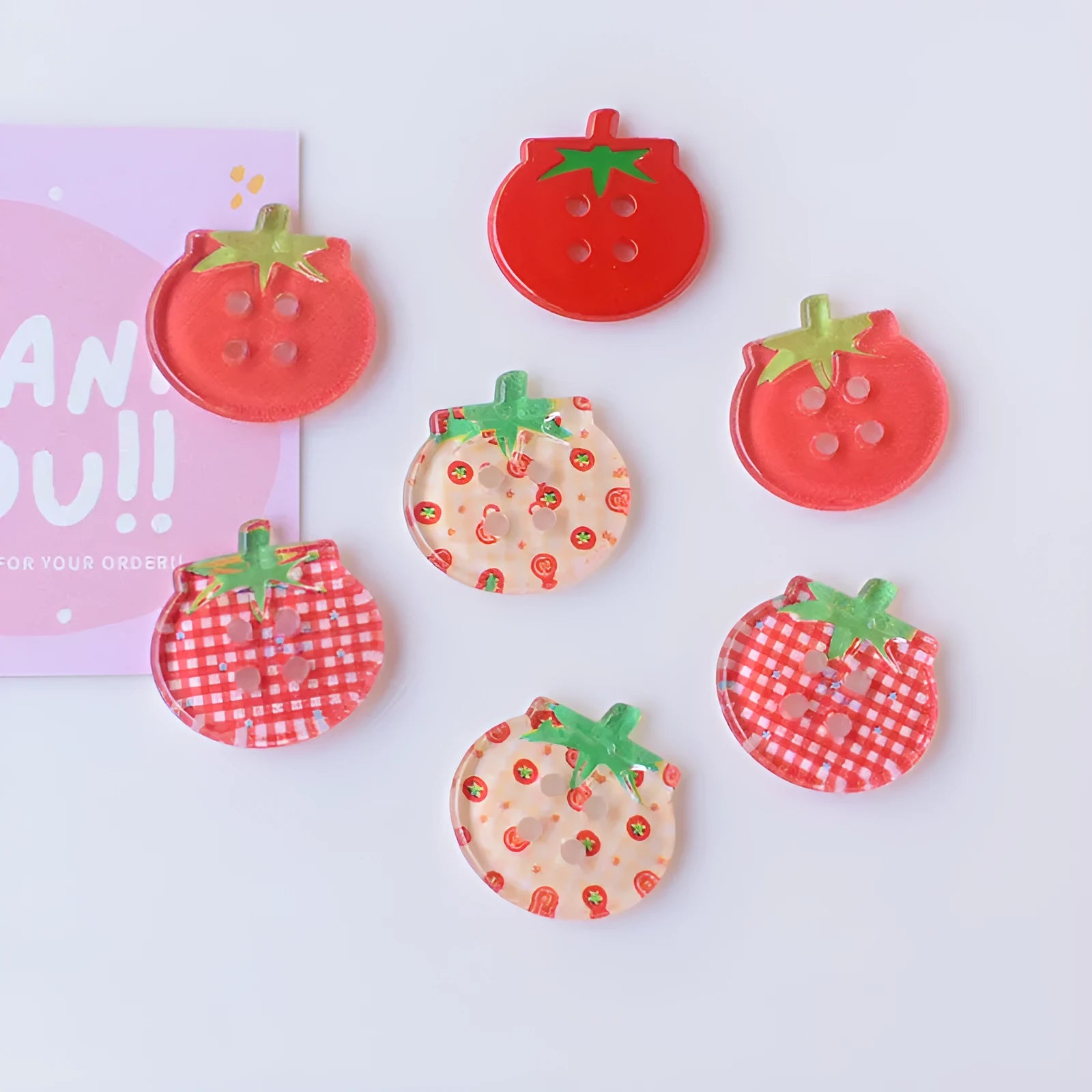 A pack of medium-sized plastic tomato button ornaments in mixed colours including red plaid and cherry tomato print.