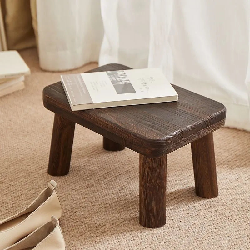 Solid wood distressed finish shoe changing stool on a wooden floor