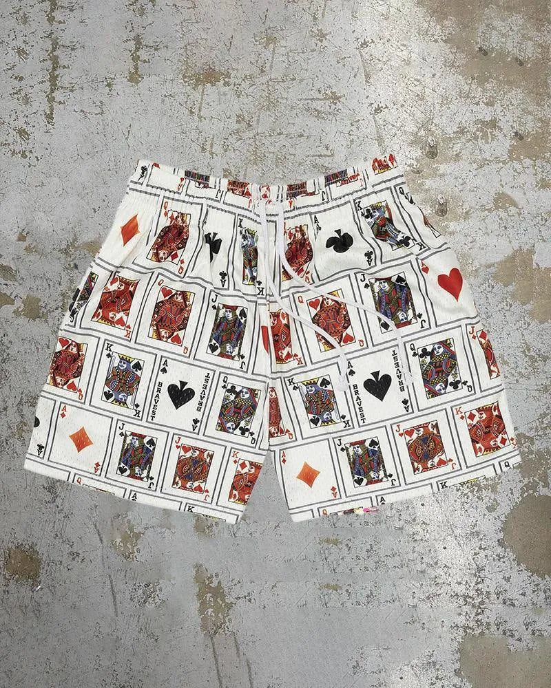 Man's loose blue digital print beach shorts with elastic waistband on a sandy background.
