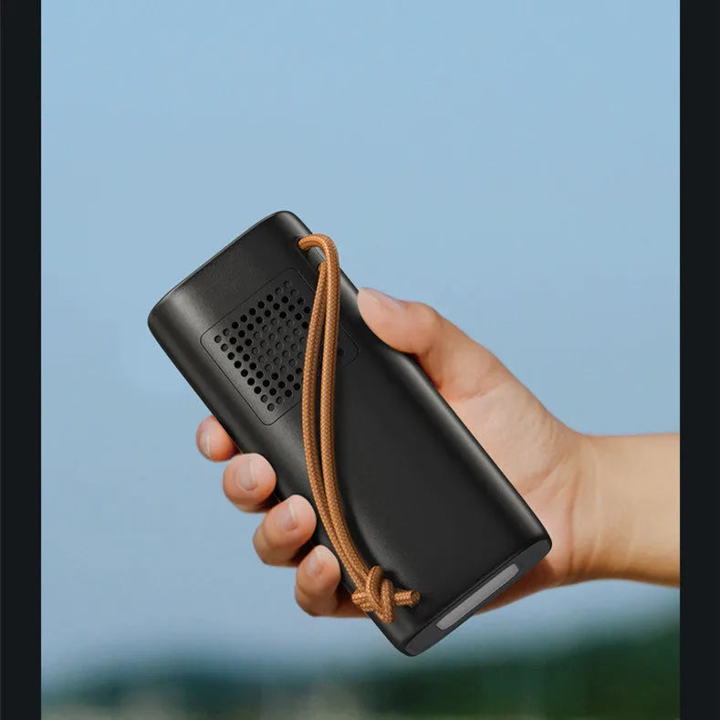 Black portable power bank with digital display, 220V socket, and USB ports on a wooden table.