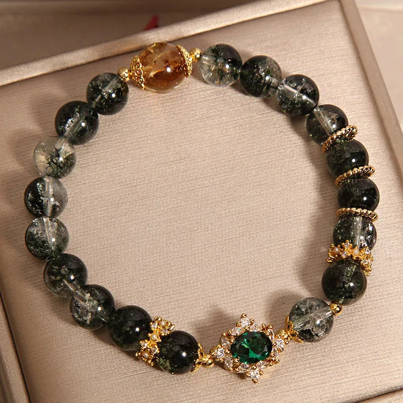Women's gold rutilated quartz crystal bracelet with green phantom quartz accents, pearls, and rhinestones.