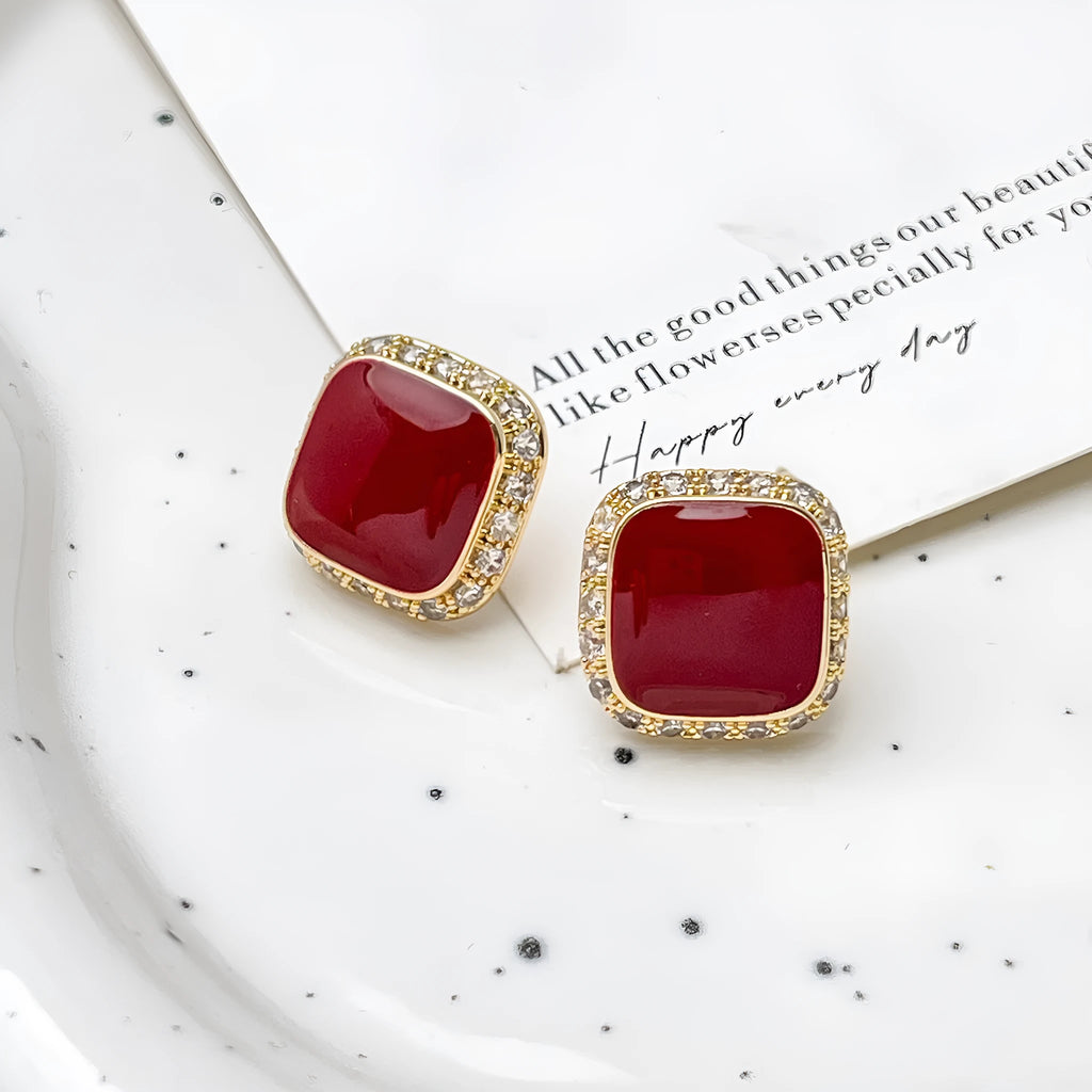 Red alloy square earrings with an inlaid geometric pattern, shown from the front.