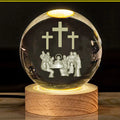 White crystal ball ornament with internal Christian cross figure on a wooden light-up base.