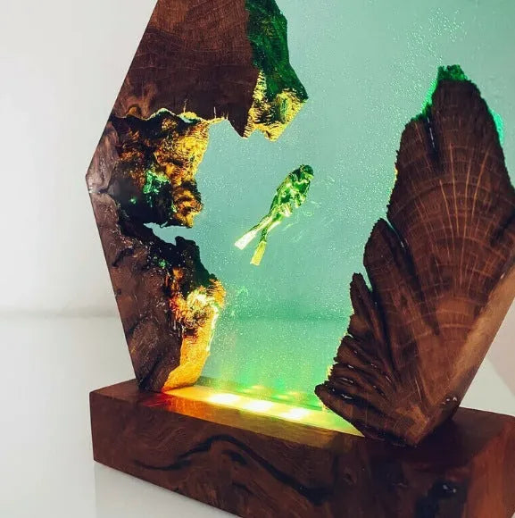 Resin luminous diver and humpback whale night light with USB cable on a shelf