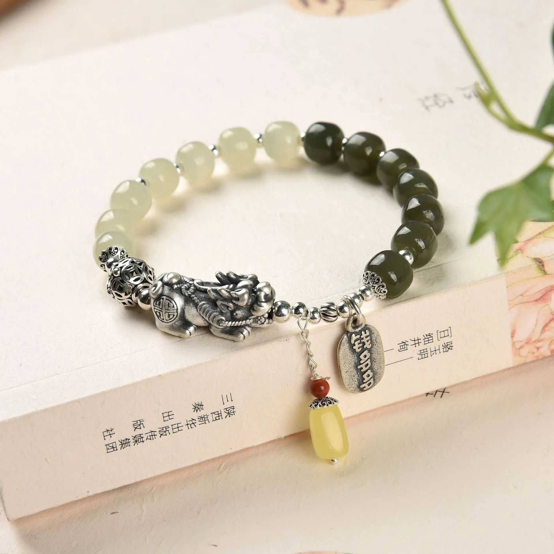 Close-up of a women's silver bracelet with Hetian jade beads and an 8x7mm retro coin charm.