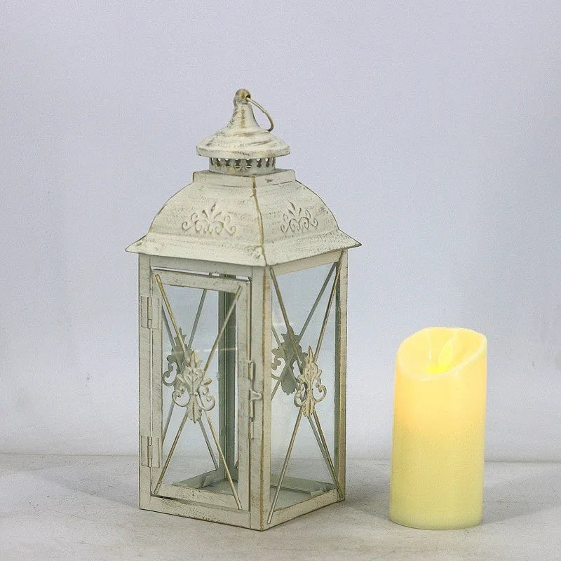 Black and white wrought iron floor standing storm lantern with tempered glass panels on a patio.