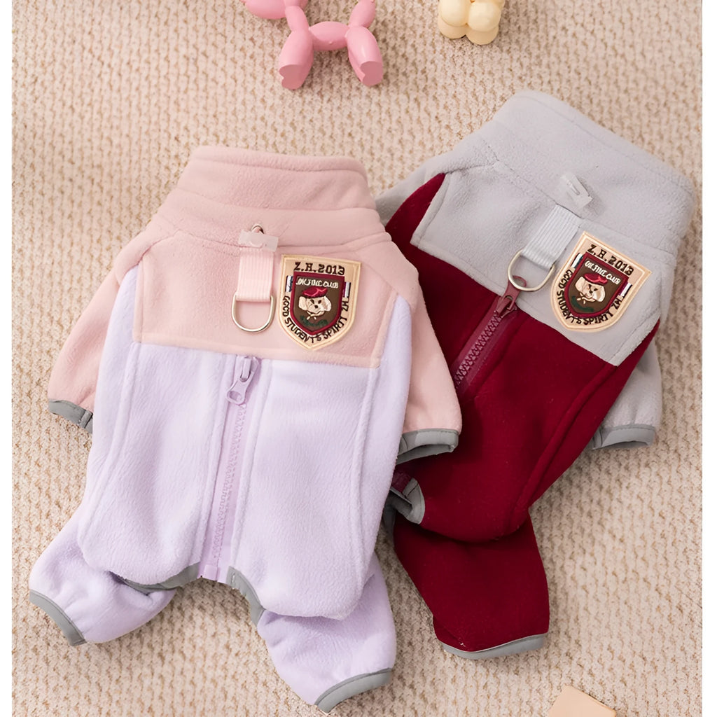 Small dog wearing a colour-block fleece jumpsuit in purple and pink, with full-zip front and leash ring