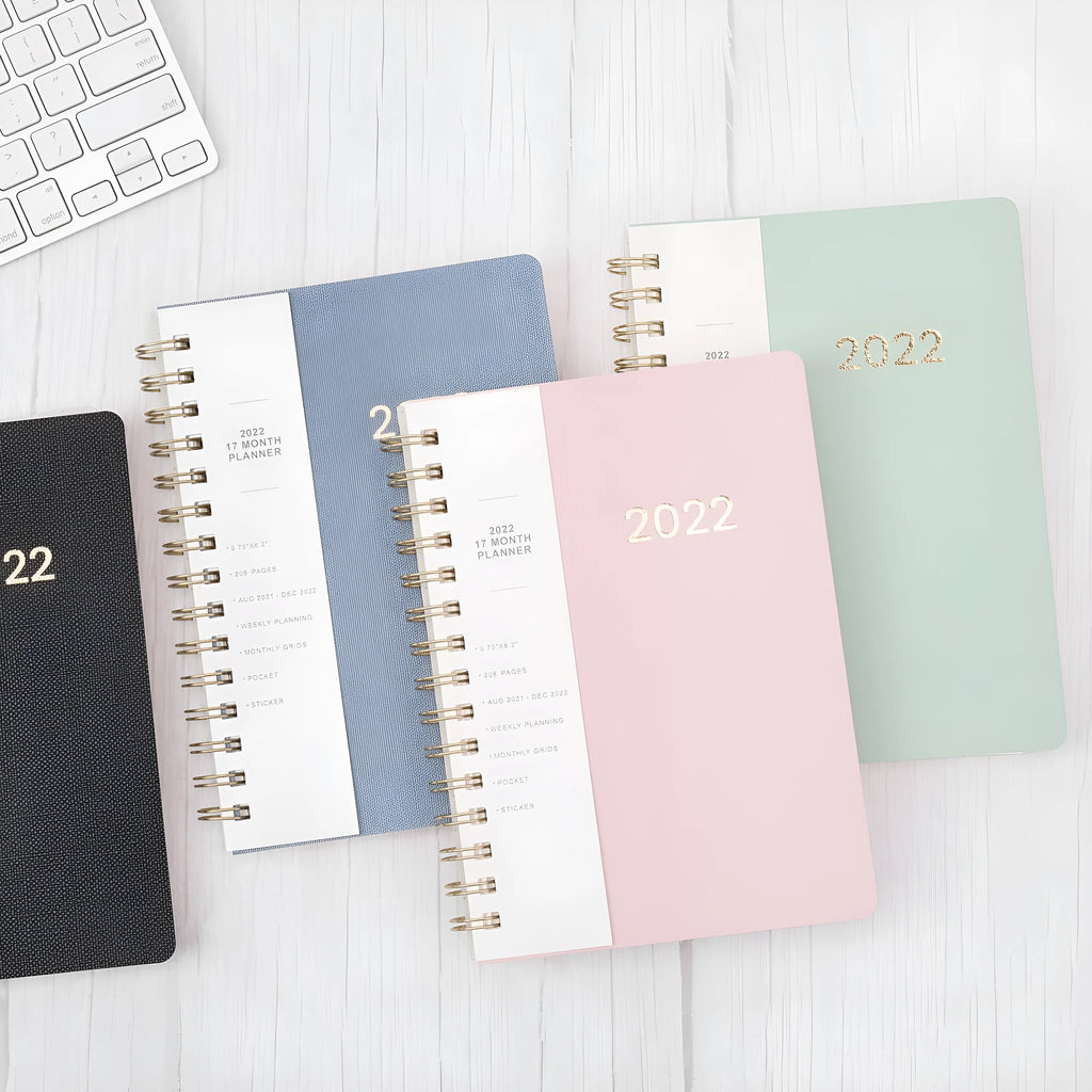 Blue A6 student weekly planner notebook with coil binding, open to show pages and pockets.